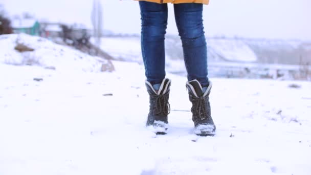 Primo piano vista verticale dal basso, i piedi di ragazza adolescente camminano sulla neve sorridente . — Video Stock