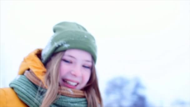 Genç çift ellerimi sarışın saçlı güzel genç kız kış günü zevk outdoorst, yeşil hipster şapkalı, yeşil ve kahverengi bir eşarp ile açık havada yürüyüş, kameraya bakarak kız — Stok video