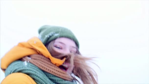 Молодая пара держит за руки красивую девушку-подростка с светлыми волосами, наслаждается зимним днем на свежем воздухе, девушка в зеленом и коричневом шарфе в зеленой хипстерской шляпе, гуляет на улице, смотрит в камеру — стоковое видео
