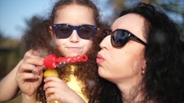 Feliz sorrindo Família, mãe e filha estão brincando, soprando bolhas de sabão no verão ao ar livre. Filmagem de stock . — Vídeo de Stock