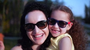 Kızı sokakta annesinin kollarında ve onu kocaman bir kucak, öpüşme ve kamera, göz gülümseyen verir yakın çekim. Ağır çekim.