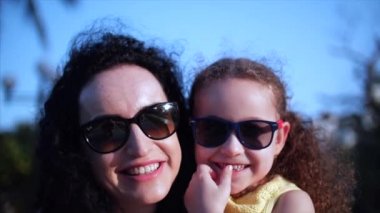 Kızı sokakta annesinin kollarında ve onu kocaman bir kucak, öpüşme ve kamera, göz gülümseyen verir yakın çekim. Ağır çekim.