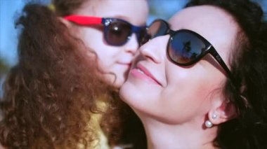 Kızı sokakta annesinin kollarında ve onu kocaman bir kucak, öpüşme ve kamera, göz gülümseyen verir yakın çekim. Ağır çekim.