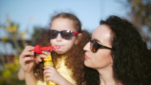 Mutlu aile gülümseyen, anne ve kızı, yaz aylarında açık sabun köpüğü üfleme oynuyorlar. Stok görüntüleri. — Stok video