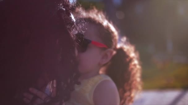 Hija en los brazos de la madre en la calle y le da un gran abrazo besándola en la nariz. Movimiento lento — Vídeos de Stock