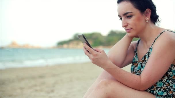 Młody szczęśliwy kaukaski kobieta za pomocą smartphone przez morze. — Wideo stockowe