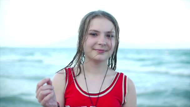 De cerca, retrato de una hermosa adolescente joven mirando a la cámara sonriendo, playa tropical en cámara lenta. Material de archivo . — Vídeos de Stock