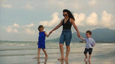 Genç aile, anne ve çocuk sahil boyunca yürüyor. Mutlu aile deniz kıyısında yürüyüş.