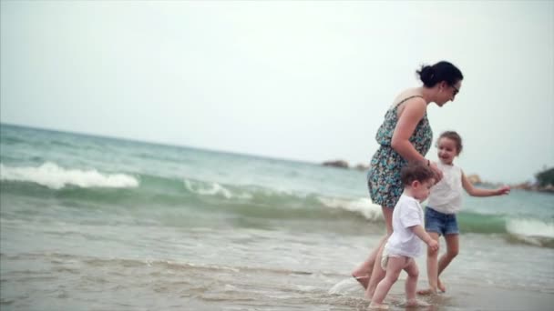 Junge Familie, Mutter und Kinder spazieren an der Küste entlang. glückliche Familie zu Fuß an der Küste. — Stockvideo