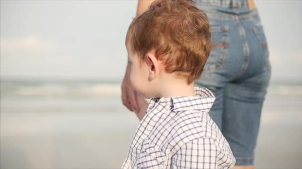 Ung familj, mor och son tittar på vågorna i havet. En lycklig familj går längs havsstranden. — Stockvideo