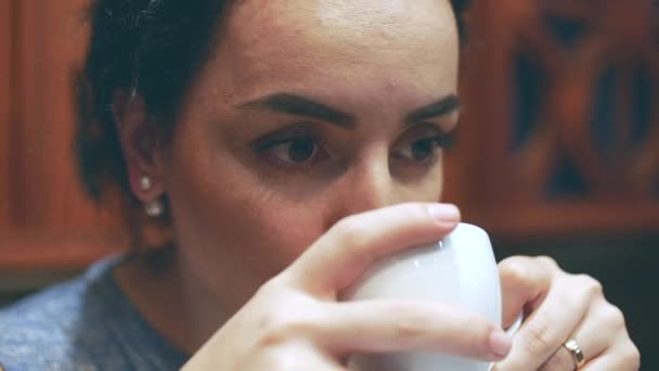 Młoda kobieta siedzi w kawiarni, uwielbia zapach i wypić filiżankę kawy — Wideo stockowe