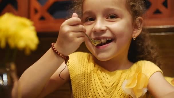 Happy child is eating a cheesecake in a cafe. Close up. — Stock Video