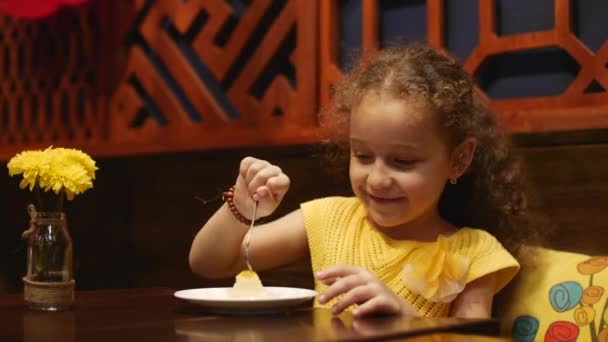 El niño feliz está comiendo una tarta de queso en un café. Material de archivo — Vídeos de Stock