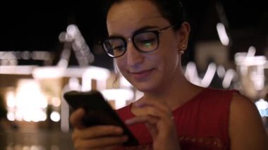 Bir gece şehirde arka plan gece şehrin sokaklarında yürürken bir cep telefonu kullanarak çekici kadın. Stok görüntüleri.