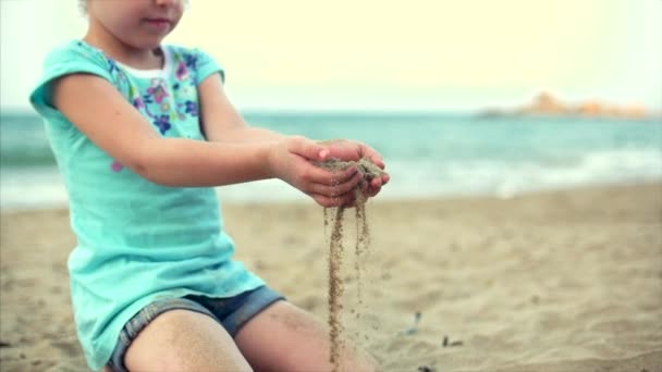 Kleines Mädchen am Strand, fröhliches kleines Baby, das mit Sand am Strand spielt. ein Kind, ein Kind, Kinder, Emotionen. — Stockvideo
