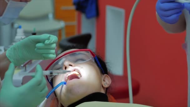 Female dentist treating patient teeth at the clinic. Female professional dentist gives an injection to a patient gum. Dental examination concept. — Stock Video