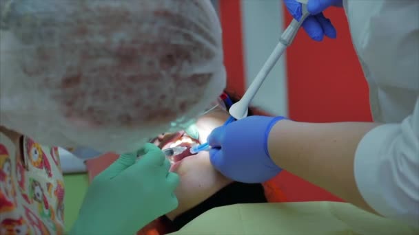 Odontóloga que trata dientes de paciente en la clínica. Dentista profesional mujer da una inyección a una encía paciente. Concepto de examen dental . — Vídeos de Stock