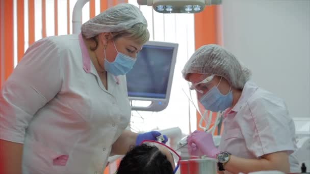 女性歯科医クリニックで女性患者に歯を治療します.仕事中の女性の専門医の組織学者。コンセプト歯科検診. — ストック動画