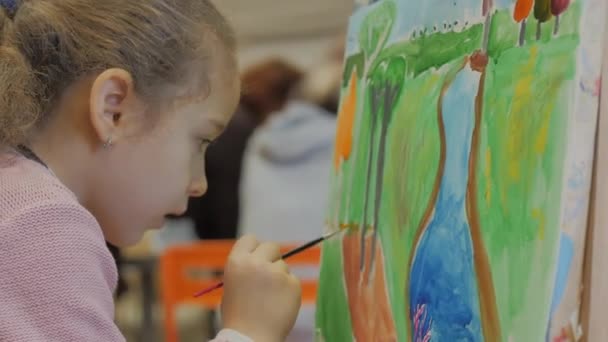Fiatal kéz a művész, kis nő művész festi a vászon ecsettel, ül egy asztal és rajzol a vászonra. Folyamat a rajz: a művészek Art Studio Hand Baby Girl vázlat a vásznon. — Stock videók