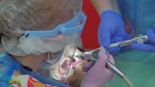 Mujer dentista tratando dientes a mujer paciente en clínica. Higiene bucal con una solución especial, limpiando la cavidad bucal con ultra sonido. Médico dentista profesional femenino en el trabajo. Examen dental — Vídeos de Stock