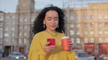 Genç Müslüman Kadın Şehir Merkezi 'nde, Akıllı Telefon ve Kahve Kullanıyor. Kavram iletişimi, online alışveriş, İyi Ruh hali, Olumlu Duygular.