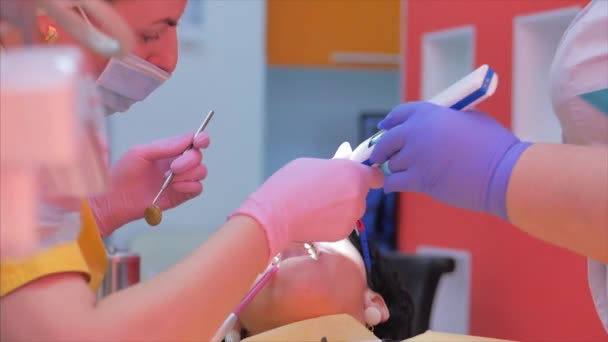 Mujer dentista tratando dientes a mujer paciente en clínica. Higiene bucal con una solución especial, limpiando la cavidad bucal con ultra sonido. Médico dentista profesional femenino en el trabajo. Examen dental — Vídeo de stock