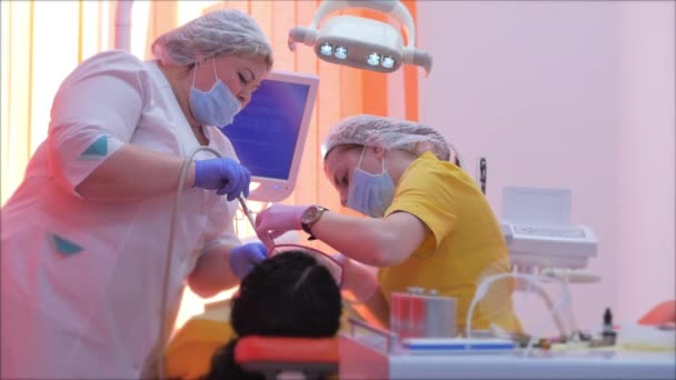 Tandarts trakteert vrouwen op een patiënt in de kliniek. Vrouwelijke professionele dokter Stomatoloog op het werk. Concept Tandheelkundige controle. — Stockvideo