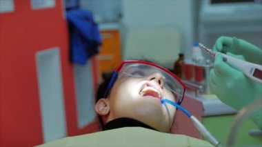 Klinikteki hastaya dişçilik yapan kadın diş hekimi. Profesyonel dişçi dişçiye diş matkabı takıyor, taşıyıcıları çıkarıyor. Diş muayenesi kavramı.