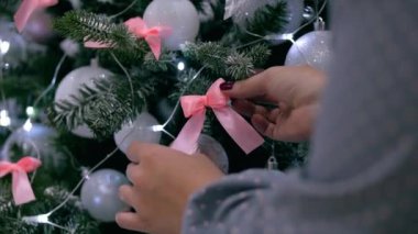 Kadın eli yakın, eller Noel ağacını yeni yıl oyuncaklarıyla süslüyor. Noel süsleri, toplar, ışıklar, çelenkler, Noel ağacına tutun.