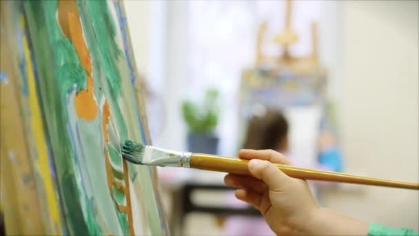 Sanatçının Genç Elleri, Küçük Kız Sanatçı Fırça ile Bir Tablo Boyar, Tablo Oturur ve Tablo Çizer. Çizim Süreci: Sanatçılar Stüdyosunda El Kızı Tabloda Çiziyor. — Stok video