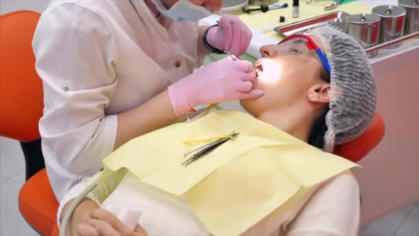 Mulher Dentista Tratando Dentes à Mulher Paciente na Clínica. Higiene oral com uma solução especial, limpeza da cavidade oral com ultra-som. Médica dentista profissional no trabalho. Exame dentário — Vídeo de Stock