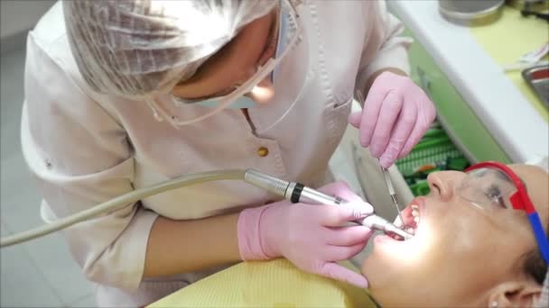 Το άτομο υποβάλλεται σε ιατρική εξέταση και θεραπεία της στοματικής κοιλότητας στον οδοντίατρο. Οδοντίατρος που φροντίζει τα δόντια της γυναίκας ασθενή στην κλινική. Γυναίκα επαγγελματίας γιατρός Στοματολόγος στην εργασία. — Αρχείο Βίντεο
