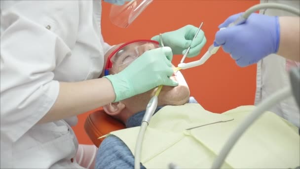 Osoba poddaje się badaniu lekarskiemu i leczeniu jamy ustnej u dentysty. Dentystka lecząca zęby pacjentce w klinice. Kobieta Lekarz Stomatolog w pracy. — Wideo stockowe