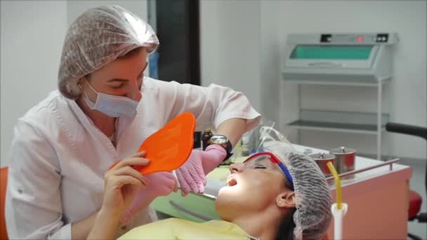 Persona sottoposta a esame medico e trattamento della cavità orale presso il dentista. Dentista donna che cura denti a paziente donna in clinica. Medico professionista femminile Stomatologo sul lavoro . — Video Stock