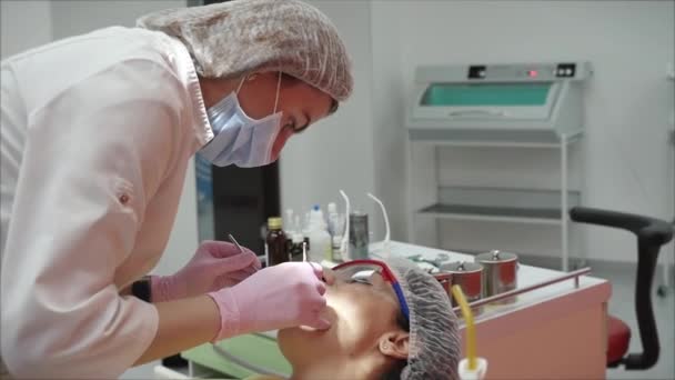 A pessoa é submetida a um exame médico e tratamento da cavidade oral no dentista. Mulher Dentista Tratando Dentes à Mulher Paciente na Clínica. Médica Estomatologista Profissional Feminina no Trabalho . — Vídeo de Stock