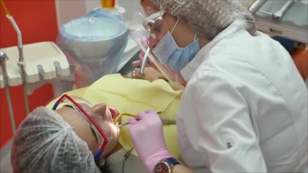 Doctora profesional Dentista en el trabajo, tratando dientes a mujer paciente en clínica. Médico estomatólogo profesional femenino en el trabajo. Equipo dental en segundo plano . — Vídeos de Stock