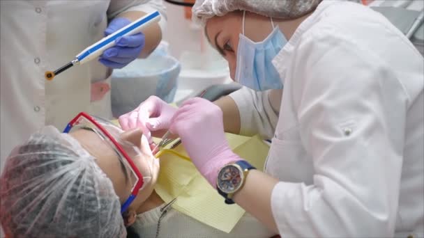 Doctora profesional Dentista en el trabajo, tratando dientes a mujer paciente en clínica. Médico estomatólogo profesional femenino en el trabajo. Equipo dental en segundo plano . — Vídeos de Stock