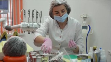 Profesyonel kadın diş hekimi klinikte dişlerini tedavi ediyor. Kadın profesyonel doktor stomatolog iş başında. Arkaplanda diş ekipmanı.