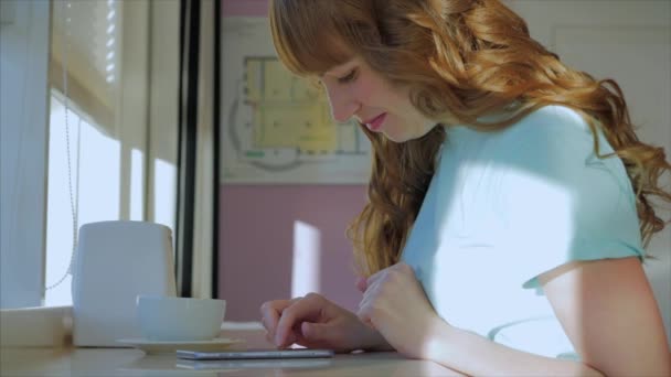 Mooie zonnige dag jonge vrouw drinkt 's morgens koffie in een cafe, het maken van Online een aankoop Gemakkelijke betaling op het internet met behulp van een mobiele telefoon of laptop. — Stockvideo