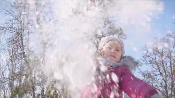 Gelukkige, leuke jeugd op een zonnige winterdag buiten. Dochter speelt met de vader in sneeuwballen, gooit een sneeuwbol direct in de camera, terwijl plezier en glimlachen kijkt naar de camera. — Stockvideo