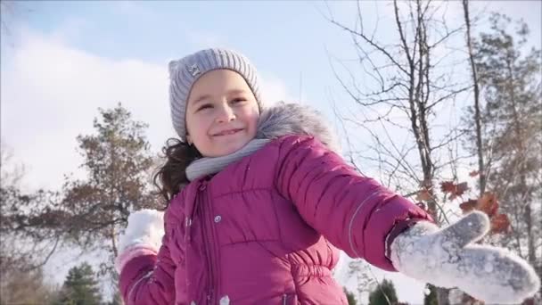 Güneşli bir kış gününde mutlu, eğlenceli bir çocukluk. Kız, babasıyla kartopu oynarken, kameraya bir kar küresi fırlatıyor, hem eğleniyor hem de gülümsüyor.. — Stok video