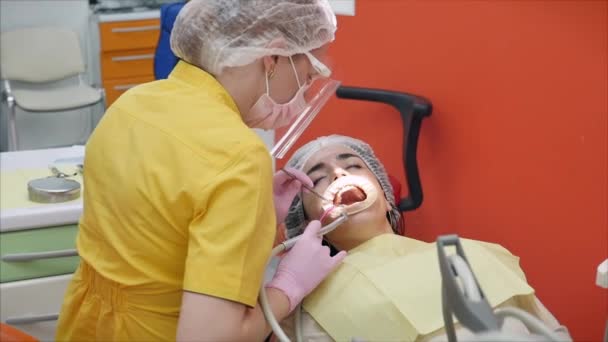 Person unterzieht sich einer ärztlichen Untersuchung und Behandlung der Mundhöhle beim Zahnarzt. Zahnärztin, die Zähne einer Patientin in der Klinik behandelt. Zahnärztin bei der Arbeit. — Stockvideo