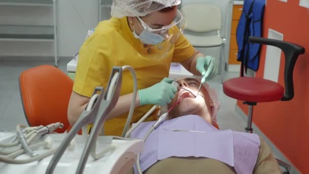 Close-up Vrouwelijke handen Professionele dokter Stomatoloog op het werk. Persoon ondergaat een medisch onderzoek en behandeling van de mondholte bij de tandarts. — Stockvideo