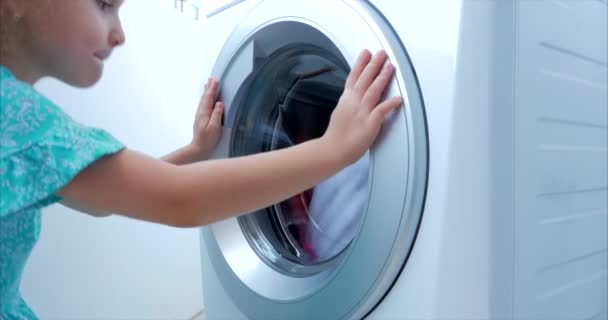 Schattig kind kijkt in de wasmachine. Cilinder draaiende machine. Concept Wasserij wasmachine, industrie Wasserij service. — Stockvideo