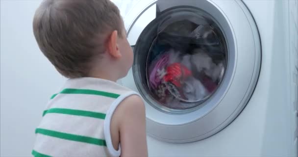 Leuk jongetje kijkt in de wasmachine. Cilinder draaiende machine. Concept Wasgoed Wasmachine, Industrie Wasgoed Service. — Stockvideo