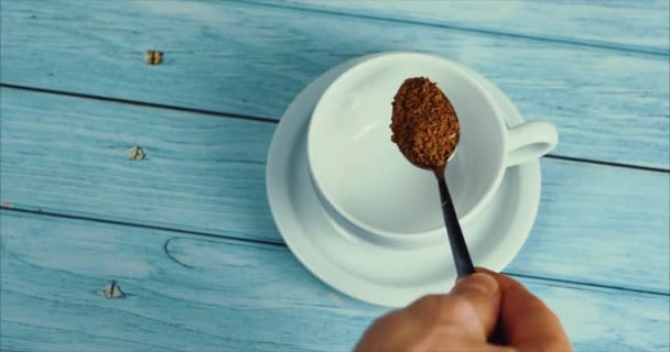 Pleine cuillère de café. Café en poudre tombant dans la tasse. Tasse blanche de café évaporant sur la table avec haricot rôti. Café au ralenti verser . — Video