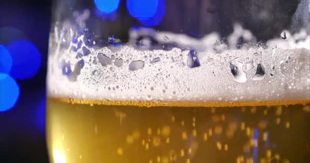 Glas Champagne of Bier in een glas op de achtergrond van feestdagen of nieuwjaarslicht, op een mooie achtergrond Fris bier, koud licht bier in een glas met druppels water. Vers en schuim. 4k — Stockvideo