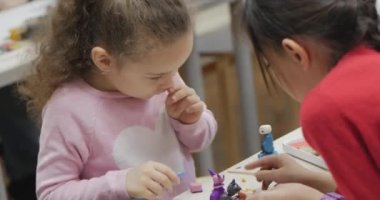 Masada oturan şirin küçük çocuklar kreşteki renkli modelleme plastiklerinden farklı figürler sergiliyor. Çocuklarda Modellik Sanatının Geliştirilmesi.