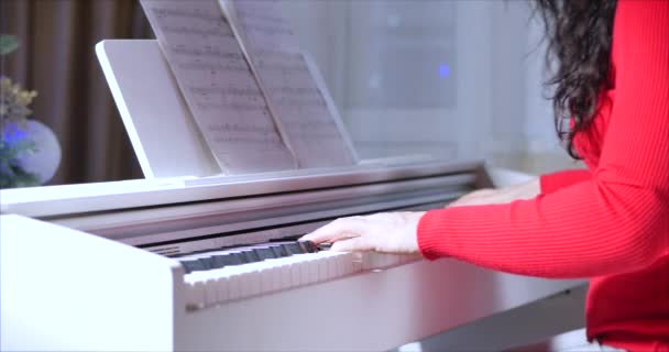 女性または少女学生またはプロのピアニストは、美しい白いピアノでクラシック音楽を演奏し、ピアニストの手はスローモーションで閉じます。ピアノキーは暗い色で閉じます。4k — ストック動画