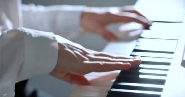 Kadın ya da Kız Öğrenci ya da Profesyonel Piyanist Güzel Beyaz Piyano 'da Klasik Müzik Çalıyor Noel ağacının arka planına karşı bir Noel Tatili ve yanıp sönen Yeni Yıl Işıkları. Piyanistlerin elleri.